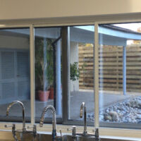 Three panel sliding fly screen system Three-panel horizontal sliding fly screen on a commercial kitchen window