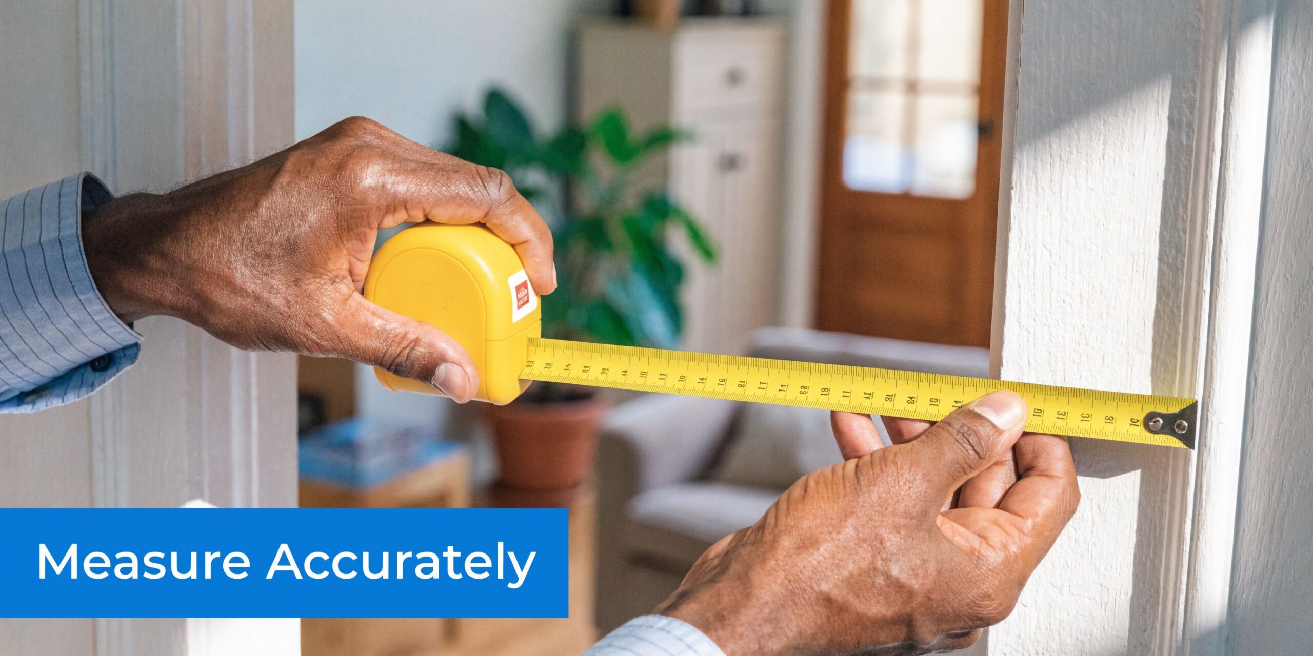 Close up of a person using a yellow tape measure to gauge the width of a door frame.