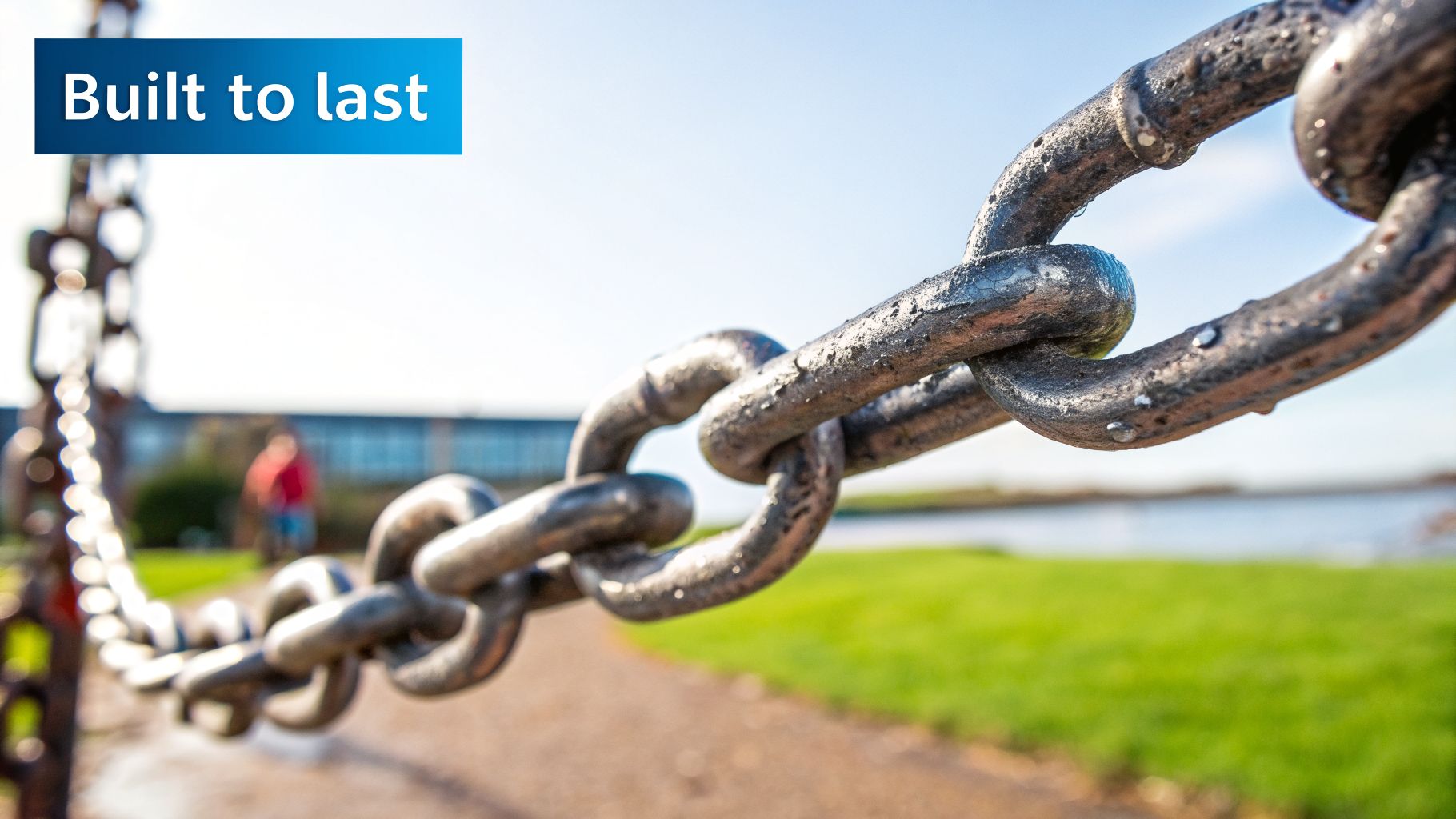 Close-up of a strong, weathered metal chain outdoors with water droplets, signifying durability.